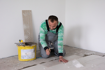 Image showing worker installing the ceramic wood effect tiles on the floor