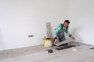 Image showing worker installing the ceramic wood effect tiles on the floor