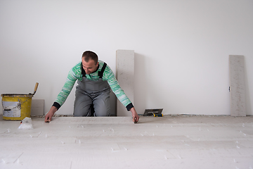 Image showing worker installing the ceramic wood effect tiles on the floor