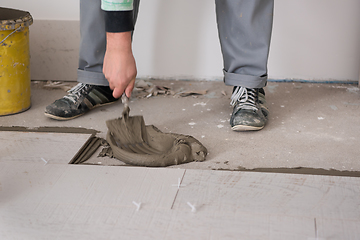 Image showing worker installing the ceramic wood effect tiles on the floor