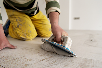 Image showing Tilers filling the space between ceramic wood effect tiles