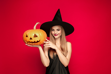 Image showing Young woman in hat as a witch on red background