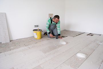 Image showing worker installing the ceramic wood effect tiles on the floor