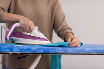 Image showing Red haired woman ironing clothes at home