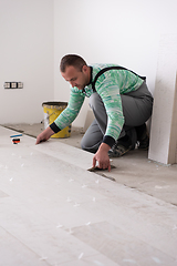 Image showing worker installing the ceramic wood effect tiles on the floor