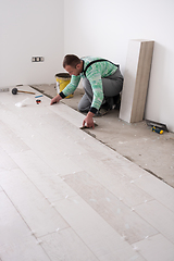 Image showing worker installing the ceramic wood effect tiles on the floor