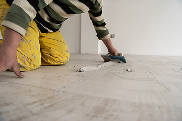 Image showing Tilers filling the space between ceramic wood effect tiles