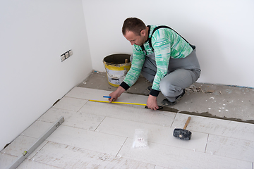 Image showing worker installing the ceramic wood effect tiles on the floor