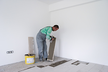 Image showing worker installing the ceramic wood effect tiles on the floor