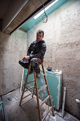 Image showing portrait of construction worker while sitting on the ladder