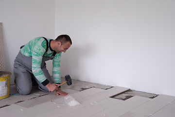 Image showing worker installing the ceramic wood effect tiles on the floor