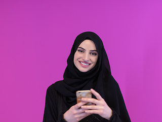 Image showing muslim business woman using smartphone on pink background