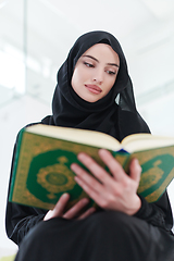 Image showing young muslim woman reading Quran at home