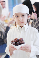 Image showing little muslim boy holding a plate full of sweet dates