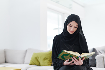 Image showing young muslim woman reading Quran at home