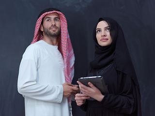 Image showing muslim couple using modern technology in front of black chalkboa