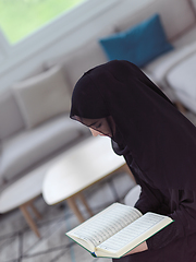 Image showing young muslim woman reading Quran at home