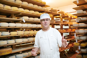 Image showing Cheese maker at the storage with shelves full of cow and goat cheese