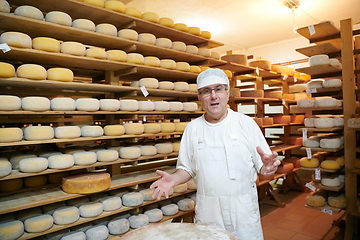 Image showing Cheese maker at the storage with shelves full of cow and goat cheese