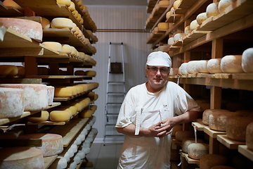 Image showing Cheese maker at the storage with shelves full of cow and goat cheese