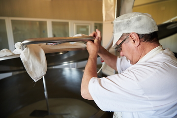 Image showing Cheese production cheesemaker working in factory