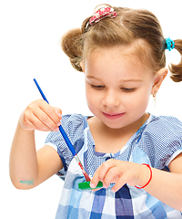 Image showing Little girl is painting with gouache