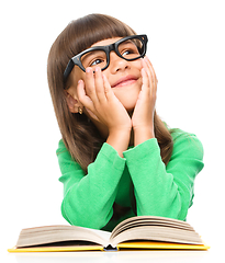 Image showing Young girl is daydreaming while reading book