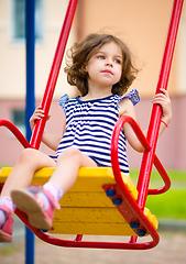 Image showing Young happy girl is swinging in playground