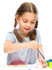 Image showing Little girl is painting with gouache