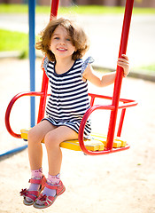 Image showing Young happy girl is swinging in playground