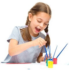 Image showing Little girl is painting with gouache