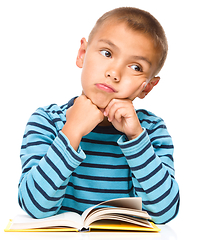 Image showing Young boy is daydreaming while reading book