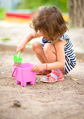 Image showing Little girl is playing with sand in playground