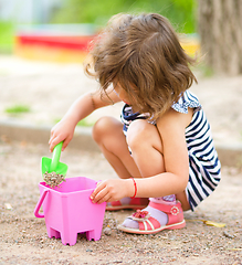 Image showing Little girl is playing with sand in playground