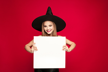 Image showing Young woman in hat as a witch on red background