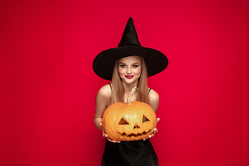 Image showing Young woman in hat as a witch on red background