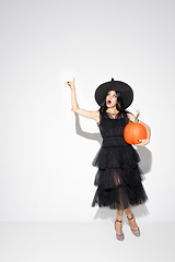 Image showing Young woman in hat and dress as a witch on white background