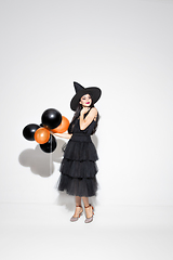 Image showing Young woman in hat and dress as a witch on white background