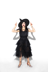 Image showing Young woman in hat and dress as a witch on white background