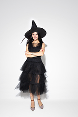 Image showing Young woman in hat and dress as a witch on white background