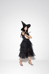 Image showing Young woman in hat and dress as a witch on white background