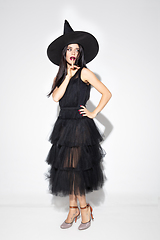 Image showing Young woman in hat and dress as a witch on white background