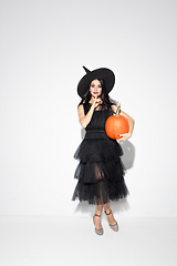 Image showing Young woman in hat and dress as a witch on white background