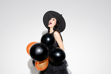 Image showing Young woman in hat and dress as a witch on white background