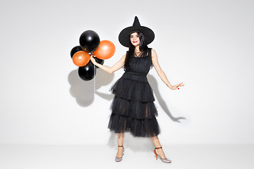 Image showing Young woman in hat and dress as a witch on white background