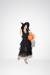 Image showing Young woman in hat and dress as a witch on white background