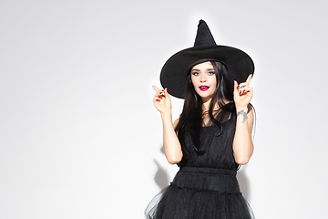 Image showing Young woman in hat and dress as a witch on white background