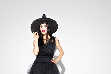 Image showing Young woman in hat and dress as a witch on white background