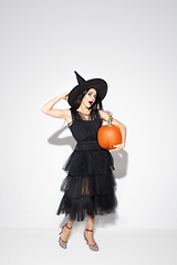 Image showing Young woman in hat and dress as a witch on white background