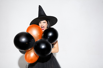 Image showing Young woman in hat and dress as a witch on white background